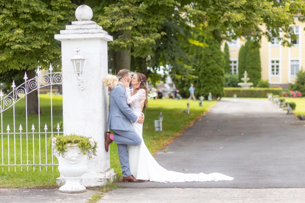 Brautpaar feiert auf Schloß Wulkow und küsst sich am Tor
